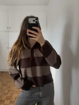 Sweater de tejido bremer fino con diseño de rayas horizontales en tonos marrón y tostado, cuello polo con botones y mangas largas.