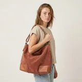 Bolso de eco cuero con textura símil gamuza en color marrón terracota, con detalles de refuerzo en eco cuero liso color tostado en las esquinas inferiores y asas. Cuenta con gran capacidad, ideal para uso diario.