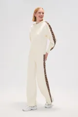 Pantalon de tejido de punto color crema, de corte ancho y tiro alto. Presenta una franja lateral con estampado animal print a lo largo de ambas piernas.