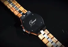 Reloj cronógrafo con caja de madera de zebrano y bisel técnico de acero negro. La esfera es plateada con subdiales de madera, indicador de fase lunar y fechador. La malla combina eslabones de acero inoxidable con madera de zebrano.