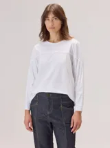 Remera de manga larga color blanco, con cuello redondo y detalle de costura horizontal a la altura del pecho. Confeccionada en algodón con spandex, presenta un corte holgado y puños simples.