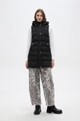 Chaleco acolchado negro con capucha ajustable mediante cordones, cierre frontal con botones a presión y bolsillos laterales con cierre.