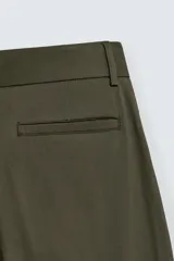 Pantalón negro de corte relaxed fit y estilo wide leg, con pliegues frontales dobles, bolsillos delanteros y detalle de bolsillos traseros de vivo. Cierre frontal cruzado con cremallera y gancho metálico oculto.