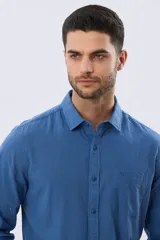Camisa de lino de manga larga en color beige, con cuello camisero, cierre frontal de botones y un bolsillo ojal en el pecho.