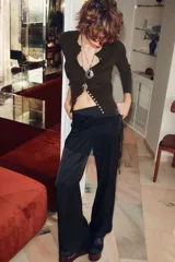 Pantalón largo de satén negro con pareo de encaje superpuesto en la cintura y lazada lateral. Cierre lateral con cremallera oculta.