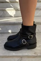 Bota corta de cuero charolado color bordó, con suela track negra, cierre lateral y tiras decorativas con hebillas metálicas plateadas.