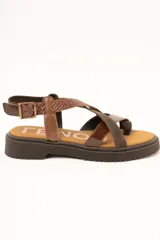 Sandalias de cuero color marrón con suela track, tiras cruzadas en el empeine con diferentes texturas y acabados, y tira ajustable al tobillo con hebilla metálica.