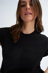 Camiseta sin mangas negra con cuello redondo, hombros estructurados y un volante peplum en la parte inferior.