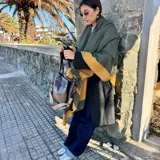 Ruana de material símil cachemira, de diseño bicolor en tonos gris y lila con bandas anchas en los bordes.