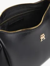 Cartera tipo hobo Tommy Hilfiger de acabado liso en color negro, con cierre de cremallera superior, asa corta de mano y correa tejida ajustable y extraíble en blanco y negro. Incluye detalle de logo metálico en relieve en la parte delantera y herrajes dorados.