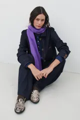 Chaqueta de denim azul oscuro con cierre frontal de botones, cuello clásico y bolsillos laterales. Presenta un diseño de corte recto y mangas largas con puños abotonados.