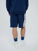 Bermuda de felpa azul marino con cordón ajustable en la cintura, bolsillos laterales y el logo de Umbro bordado en blanco en la pierna izquierda.