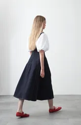 Vestido midi sin mangas de color azul oscuro, con escote cuadrado y silueta evasé. Presenta costuras a contratono en color blanco que recorren verticalmente el diseño, aportando estructura y un detalle gráfico. Confeccionado en tejido con cuerpo y caída firme.