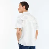 Camisa de manga corta con diseño de rayas verticales azules sobre fondo blanco, cuello camisero, cierre frontal con botones y bolsillo aplicado en el pecho.