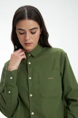 Camisa verde militar de manga larga con cuello clásico, cierre frontal con botones y bolsillo en el pecho con logo bordado. Corte recto.