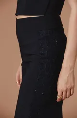 Pantalón de mujer blanco de corte sastrero, tiro alto y silueta amplia de pernera recta con detalles de flecos o pedrería en los laterales.