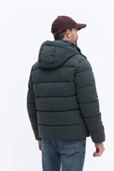Campera puffer con capucha integrada, cierre frontal cubierto y bolsillos laterales. Confeccionada en nylon, presenta un diseño acolchado y funcional ideal para climas fríos.