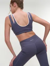 Top deportivo rosa con efecto layering, escote redondo bajo y tirantes dobles. Presenta el logo de la marca en tono oscuro en el frente.