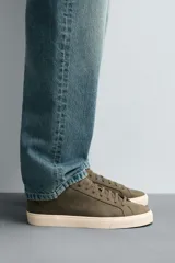 Zapatilla de cordones color beige, con parte superior lisa, horma redonda, forro interior a contraste y suela con ligera textura.