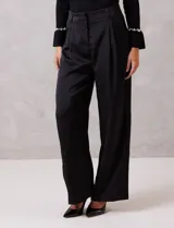 Pantalón palazzo de satén color negro, de tiro alto con pretina delantera estructurada, pasadores para cinturón y bolsillos laterales. Presenta una caída fluida y amplia, con elástico en la parte posterior de la cintura para mayor ajuste.