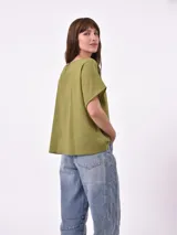 Blusa de corte holgado color oliva, con escote en V y mangas cortas con caída natural.