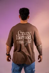 Remera oversize marrón de algodón elastizado con estampado en la espalda que incluye el texto "Crazy Hermod movement" y un diseño de zapatilla alada.
