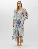 Conjunto compuesto por un vestido midi de gasa con estampado floral en tonos violeta, azul y crema, con escote en V, tirantes anchos y ruedo asimétrico con volados. Incluye una chaqueta corta tipo torera de mangas 3/4 confeccionada en la misma tela. Posee forro interno a tono.