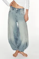 Jeans de mezclilla de tiro medio con diseño amplio tipo balloon, costuras marcadas y bajo con puño elástico. Cuenta con bolsillos delanteros y traseros, y cierre frontal con cremallera y botón metálico.