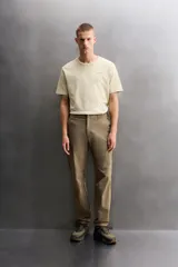 Pantalón técnico de corte regular fit en color marrón, confeccionado en tejido elástico y compacto. Cuenta con cintura ajustable con cordón interior, bolsillos frontales, bolsillo trasero con cierre oculto y bolsillo lateral con cierre en la pernera. El bajo es ajustable mediante botones a presión.