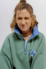 Buzo verde con cierre metálico, cuello alto y bordados.