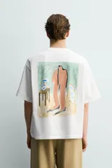 Camiseta blanca de corte relajado, con cuello redondo, manga corta y estampa frontal de texto pequeño en marrón.