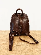 Mochila de cuero vacuno color marrón, con diseño estructurado y combinación de textura croco en el bolsillo frontal. Cuenta con un compartimento principal con cierre, un bolsillo frontal con cierre metálico y hebillas decorativas, y correas regulables.