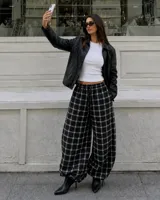 Pantalón de corte amplio y holgado con diseño a cuadros, cintura elástica con cordón ajustable y bajos regulables en las piernas.