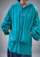 Buzo canguro oversize color turquesa, confeccionado en plush. Cuenta con capucha ajustable con cordón, un bolsillo canguro frontal y mangas largas abullonadas con puños elásticos.