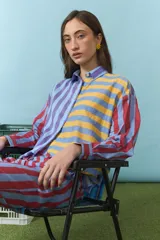 Camisa de algodón con diseño de rayas multicolor en tonos azul, amarillo y rojo. Presenta cuello clásico, cierre frontal con botones y mangas largas.