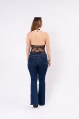 Jean de corte oxford en color azul oscuro, con silueta ajustada en la parte superior y pierna acampanada. Presenta costuras a contraste y cierre frontal con botón.
