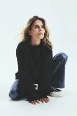 Buzo negro oversize de frisa esmerilada con cuello alto, hombros caídos, bolsillos laterales y estampa en la espalda con el logo de la marca en animal print.