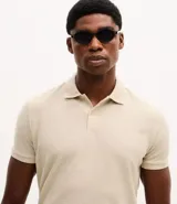 Camisa polo de corte regular, color verde oscuro, confeccionada en tejido texturizado. Presenta cuello clásico con botones frontales y mangas cortas.