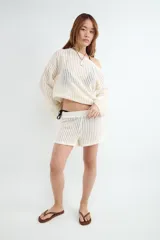 Sweater de manga larga y tejido calado color beige, con cuello redondo y diseño liviano.