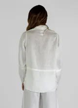 Chaqueta color amarillo de lino, con cuello camisero, cierre frontal con botones, mangas largas con puños abotonados y dos bolsillos de parche en el pecho.