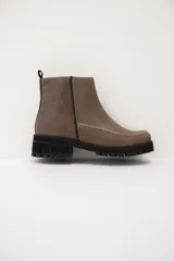 Botas cortas de cuero color visón, con suela track negra y costuras decorativas en contraste a lo largo del empeine. Cuentan con cierre lateral para facilitar su colocación.