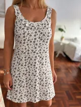 Camisón corto de algodón blanco con estampado floral en tonos oscuros, tirantes anchos y detalle de volados en el escote redondo.