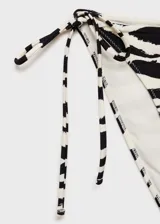 Traje de baño de dos piezas con estampado de cebra en blanco y negro. El corpiño es strapless con forma de corazón y la bombacha es de corte clásico con lazos laterales.