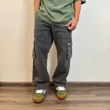 Pantalón jean cargo gris con efecto lavado, corte recto y bolsillos laterales.