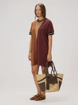 Vestido corto de punto tricolor, con diseño de bloques en tonos turquesa, celeste y azul marino. Presenta cuello redondo y puños con líneas en tonos tostado y blanco, además de un sutil bordado en el pecho.