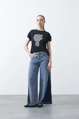 Remera blanca de manga corta con estampado frontal de un florero rojo con rayas verticales y un ramo de flores azules y rojas.