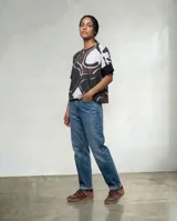 Remera de silueta amplia tipo poncho, con estampa orgánica abstracta en tonos marrones, blancos y negros. Presenta mangas cortas con terminación en color negro sólido y cuello redondo.