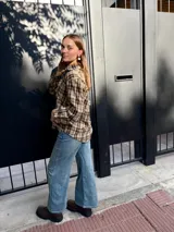 Camisa de corte holgado con estampado de cuadros escoceses en tonos beige y marrón. Presenta cuello clásico, cierre frontal con botones y mangas largas.