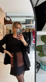 Minifalda de gabardina elastizada combinada en color negro y marrón, con detalles de tachas metálicas en las costuras verticales y en el borde inferior de la falda, y diseño con vuelo en el ruedo.