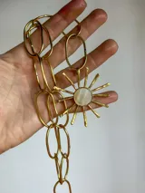 Collar con cadena de eslabones plateados y dije artesanal con forma de sol, con centro de nácar y rayos de alpaca.